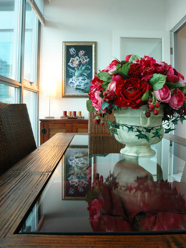 Dining room with rose floral centerpiece on a glass table.