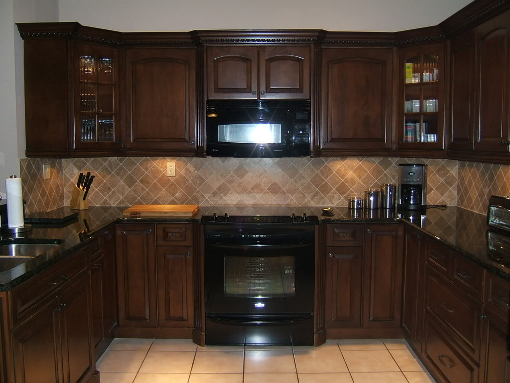 light brown kitchen cabinet with black appliances